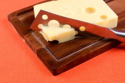 Cheese with a knife on a wooden board