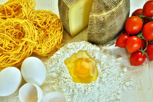 Ingredients for preparation of homemade egg pasta: flour, eggs, examples of egg pasta, tomatoes as a condiment.