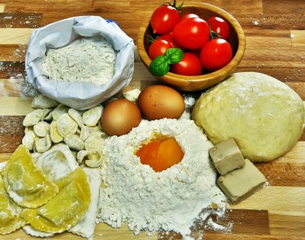 Ingredients for preparation of homemade egg pasta: flour, eggs, examples of egg pasta, tomatoes as a condiment.