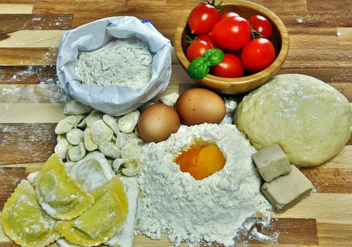 Ingredients for preparation of homemade egg pasta: flour, eggs, examples of egg pasta, tomatoes as a condiment.
