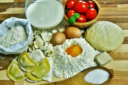 Ingredients for preparation of homemade egg pasta: flour, eggs, examples of egg pasta, tomatoes as a condiment.