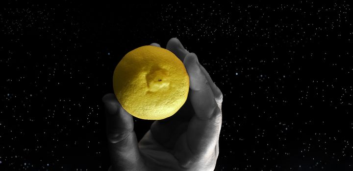 Conceptual representation of the moon as a lemon that is taken by a hand.