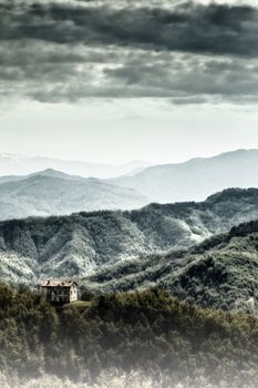 An abandoned house in the woods, in the background of the Sibillini Mountains, Italy.