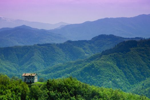 An abandoned house in the woods, in the background of the Sibillini Mountains, Italy.