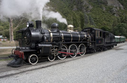 Steam locomotive slowly moving along train tracks