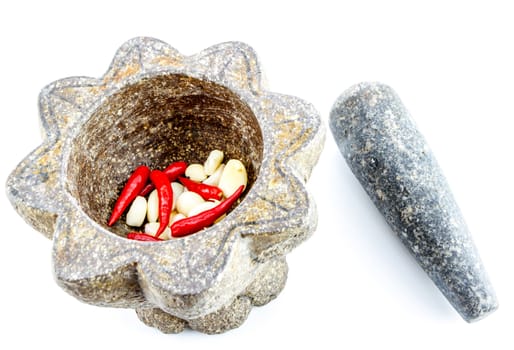 garlic and red chili pepper in stone mortar on white background