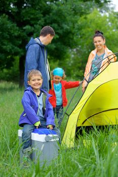 Young boy with his family near tent in camping on the nature