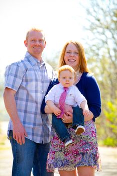 A family of three people together outdoors wearing nice clothes in this simple portrait.