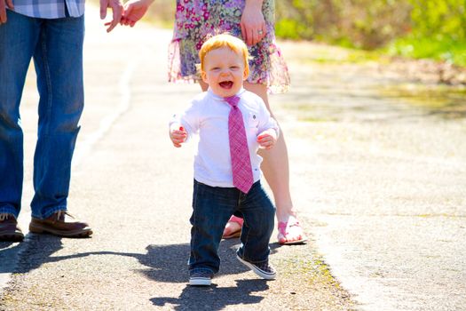 A baby boy runs away from his parents during an outdoor photo shoot with the family.