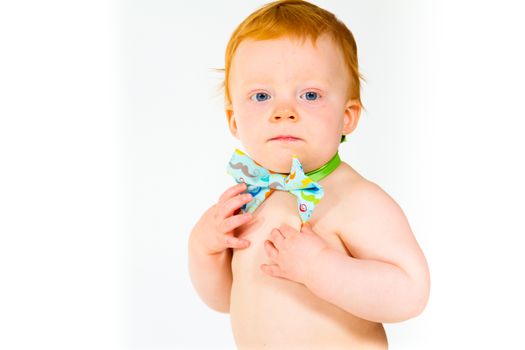 A one year old baby boy in the studio with a white background. The kid is wearing a bowtie and a diaper.