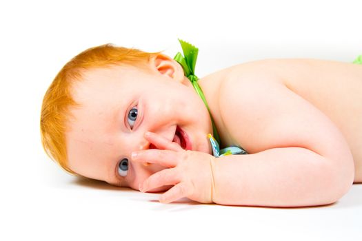 A cute one year old boy lays in the studio against a white background looking cute and happy.