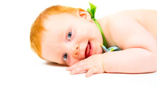 A cute one year old boy lays in the studio against a white background looking cute and happy.
