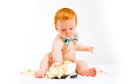 A baby boy gets to eat cake for the first time on his first birthday in this cake smash in studio against a white background.