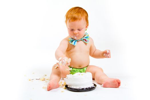 A baby boy gets to eat cake for the first time on his first birthday in this cake smash in studio against a white background.