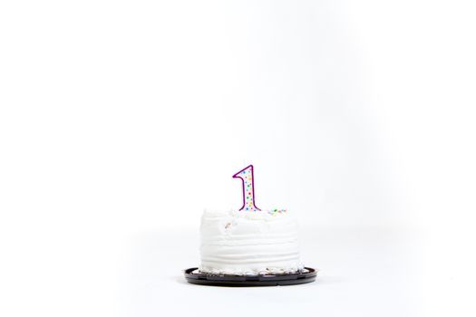 A white cake isolated against a white background in the studio for a baby first birthday.