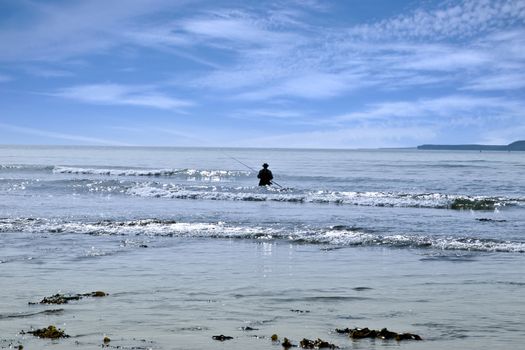 lone man fishing in the river Shannon estuary waves in Ballybunion county Kerry Ireland