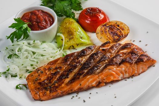 Fried fish in a plate with vegetables