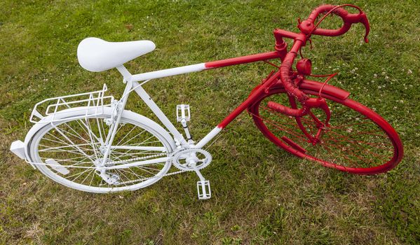 Upper view of an old bicycle painted in red and white grass.