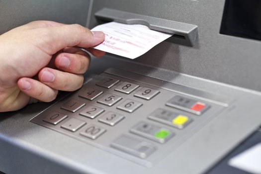 A hand taking a receipt of an Automated Teller Machine