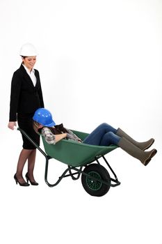 Woman pushing sleepy colleague in a wheelbarrow