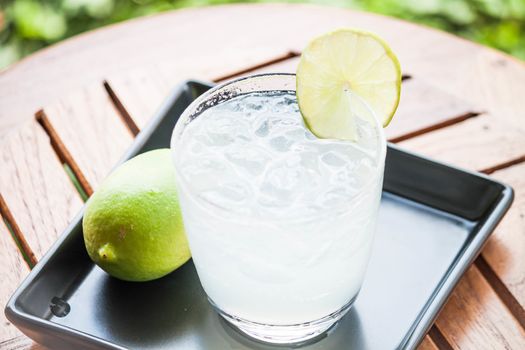 Tasty fresh lime juice with lime on wood table