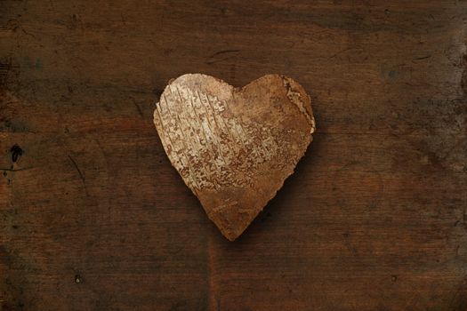 Photo of a wood heart on top of an old dark wood background.

