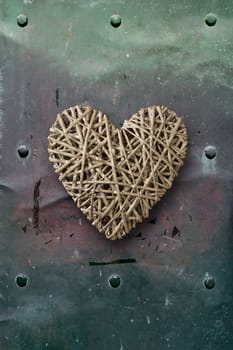 Photo of a wooden heart on top of old metal background.
