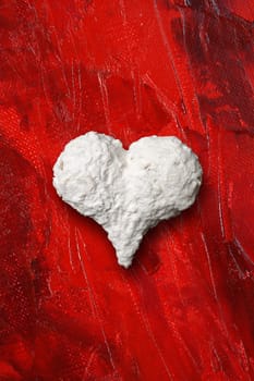 Photo of a white heart on top of red painted background.
