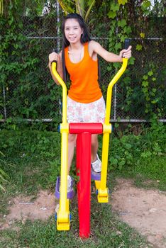 Asian Thai Girl with Exercise Machine in Public Park.