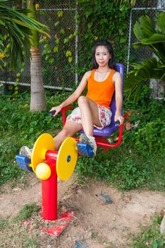 Asian Thai Girl with Exercise Machine in Public Park.