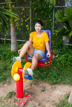 Asian Thai Girl with Exercise Machine in Public Park.