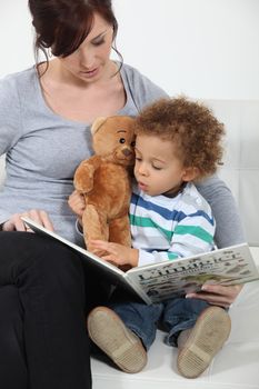 Woman reading a book to little boy on a couch