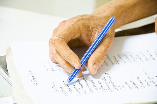 Hand of old man writing with pen