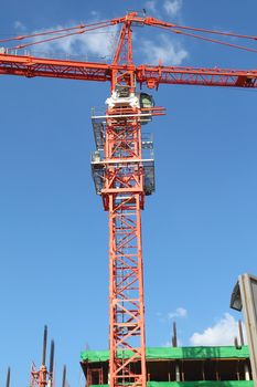 Red building crane against blue sky at construction site