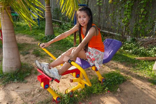 Asian Thai Girl with Exercise Machine in Public Park.