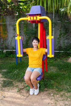 Asian Thai Girl with Exercise Machine in Public Park.
