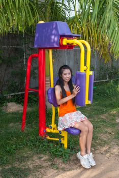 Asian Thai Girl with Exercise Machine in Public Park.