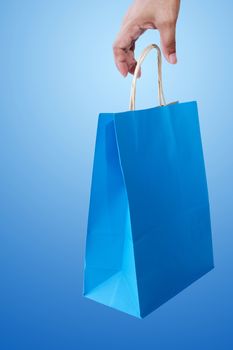 Hand and shopping bag on blue background