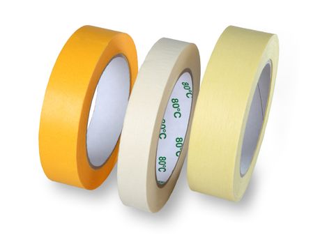Three rolls of narrow masking tape, yellow, white and brown, standing at his side, isolated on a white background.