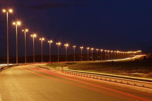 Lighting the night highway, road lighting masts, night view, horizontal photo.