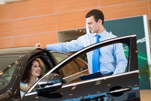 car salesman declares a young girl advantages of the new car