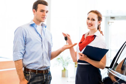 young man bought the car and takes the consultant keys from the new car