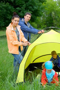 Family with two kids near tent in camping on the nature. Vertical view