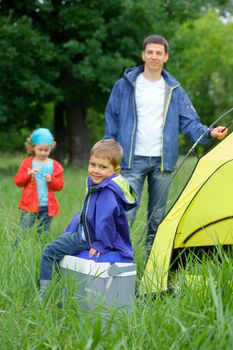 Young boy with his family near tent in camping on the nature