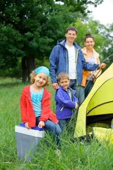 Young girl with her family near tent in camping on the nature