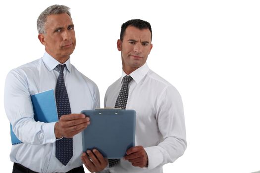 Two frowning businessmen holding clip-board