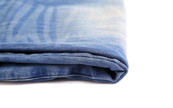A blue jeans folded on the white background close-up