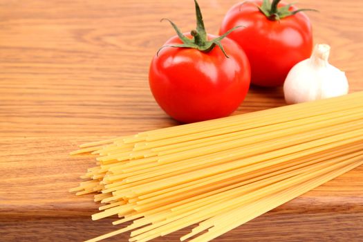 uncooked spaghetti, garlic and tomatos on a preparation board