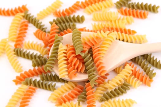 A pasta eliche tricolori and a wood spoon.