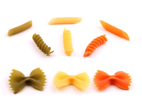 A composition of different pasta in three colors on the white background.